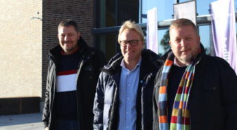 Tre män som står på rad.
