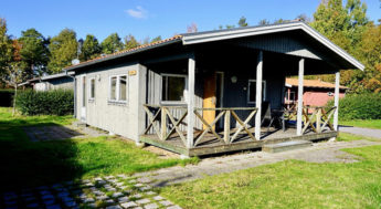 Liten stuga i trä med uteplats.