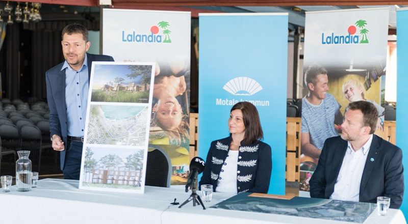 En stående man visar bilder på Lalandias tänkta etablering, bredvid sitter två personer vid ett bord.